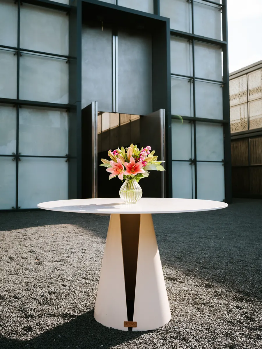 Ein Stehtisch mit Blumenstrauß vor der Fassade des Christus-Pavillons